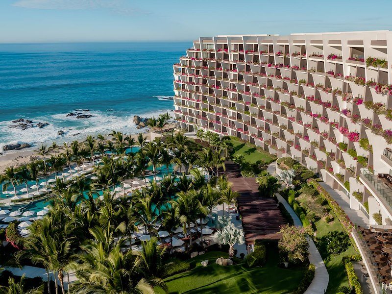 A large building with many balconies and a pool next to the ocean