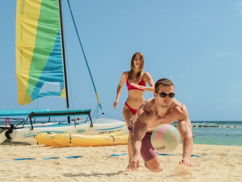 A couple playing on beach, enjoying special Gifts of now at Grand Velas Resorts.