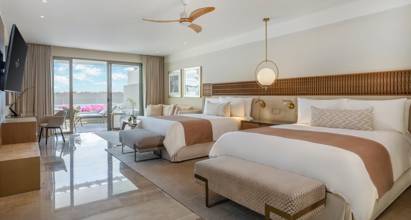 A spacious hotel room with two beds and a TV at Grand Velas Boutique Hotel Los Cabos.